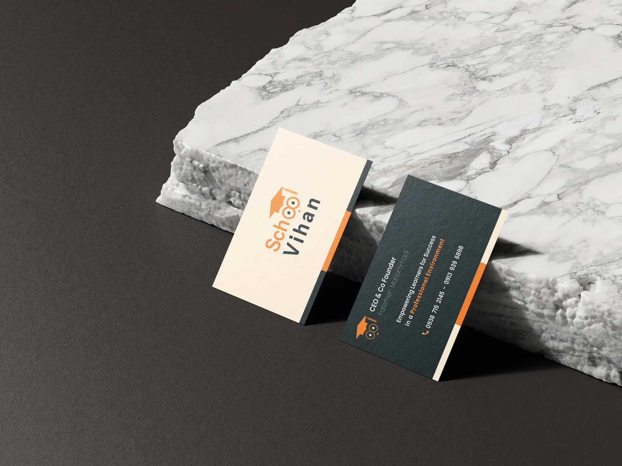 Cream and charcoal Vihan School business cards leaning on marble